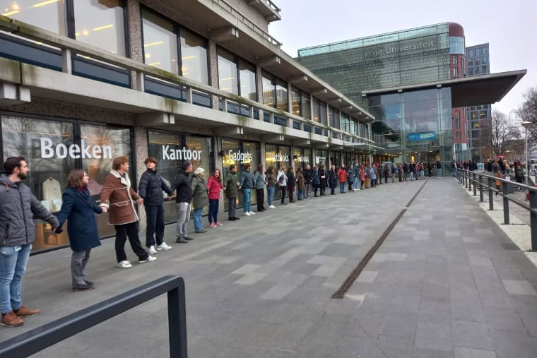 Line of people surrounding a university building holding hands in a human chain