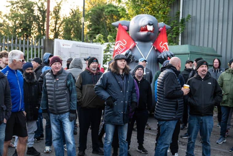 Group of workers with giant inflatable rat and unite union flags