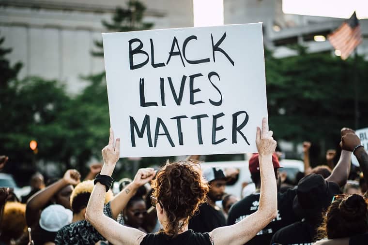 Women holds up a sign that reads Black Lives Matter
