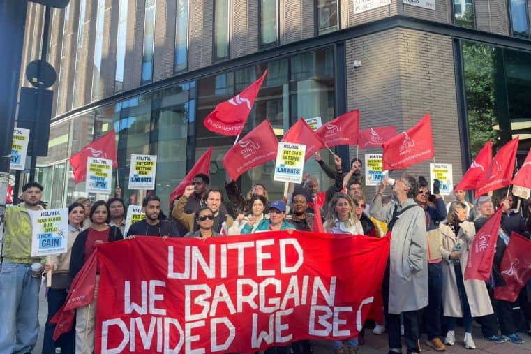 Large group of workers outside hospital with Unite flags and large red banner