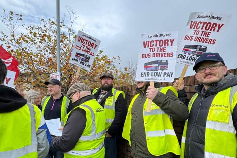 Group of Swansea bus strikers with placards and yellow hi vis jackets