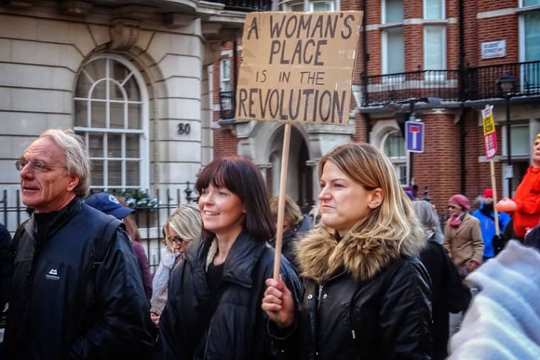 A women on a Women's March in London in 2017 holds up a sign that reads 'A woman's place is in the revolution'