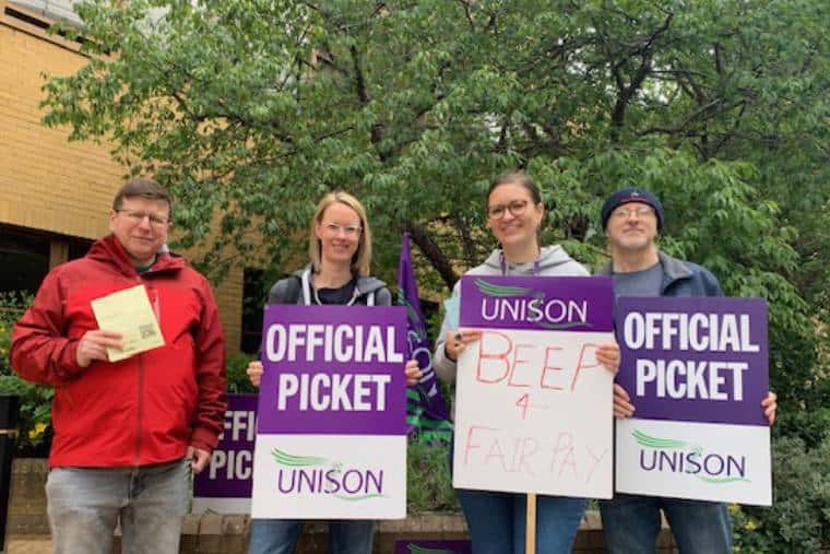 Four workers who are Unison members on a picket line at AQA