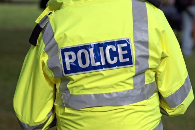 Image of the back a on-descript servicing police officer wearing a high-vis jacket
